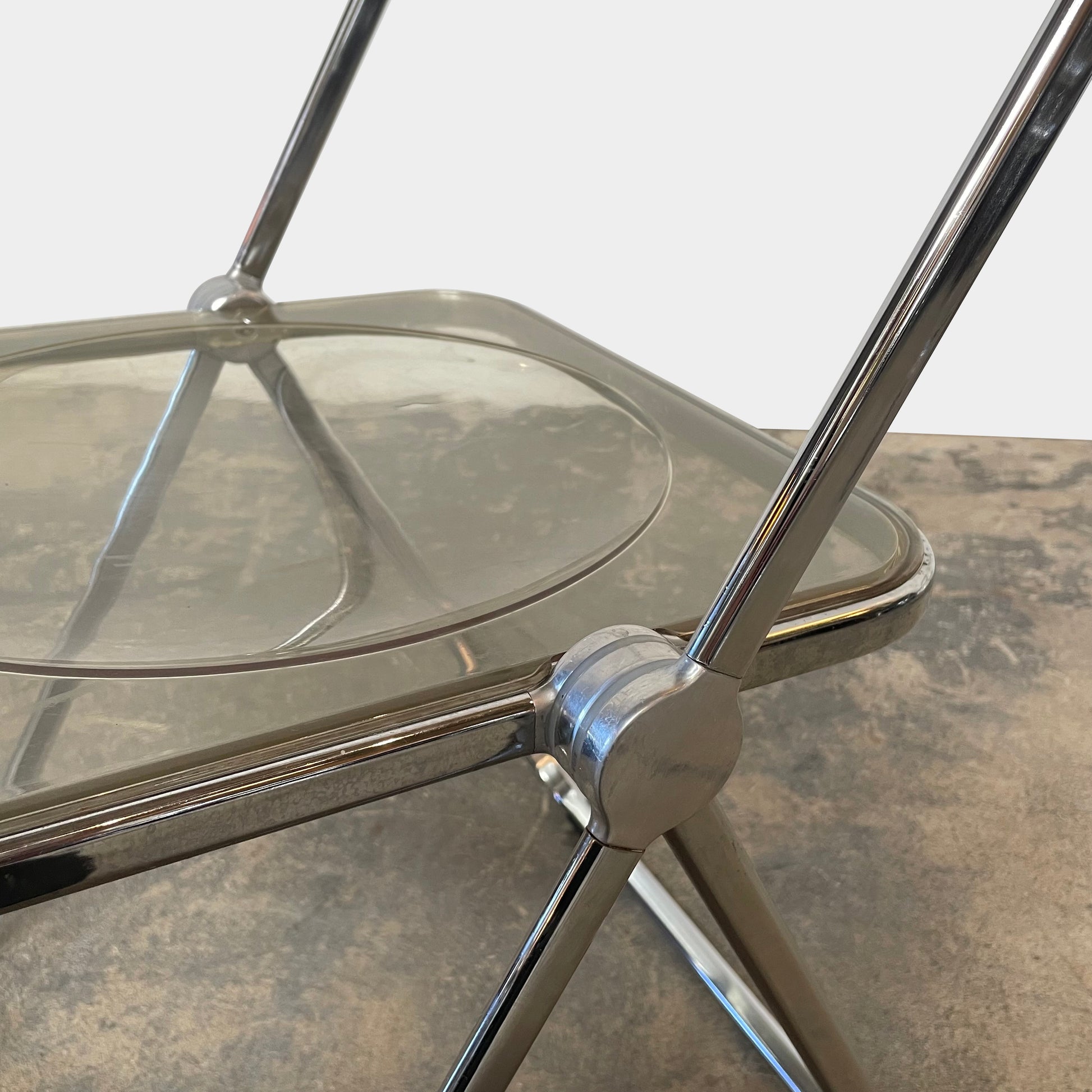 The Anonima Castelli Plia Folding Chair by Castelli, highlighted against a plain white background, echoes the iconic design of Giancarlo Piretti's Plia Folding Chairs and features the innovative "3-disc pin" mechanism.