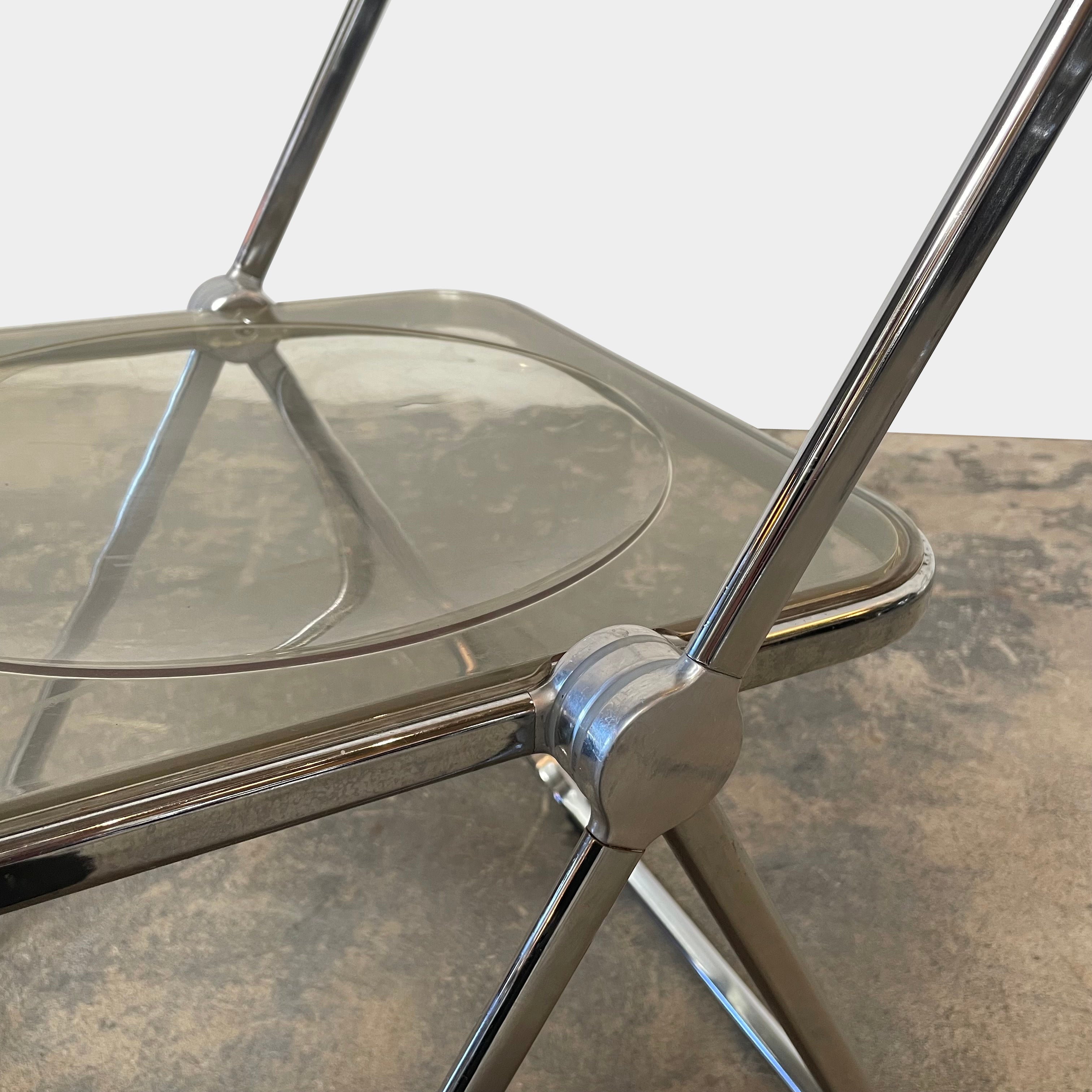 The Anonima Castelli Plia Folding Chair by Castelli, highlighted against a plain white background, echoes the iconic design of Giancarlo Piretti's Plia Folding Chairs and features the innovative "3-disc pin" mechanism.