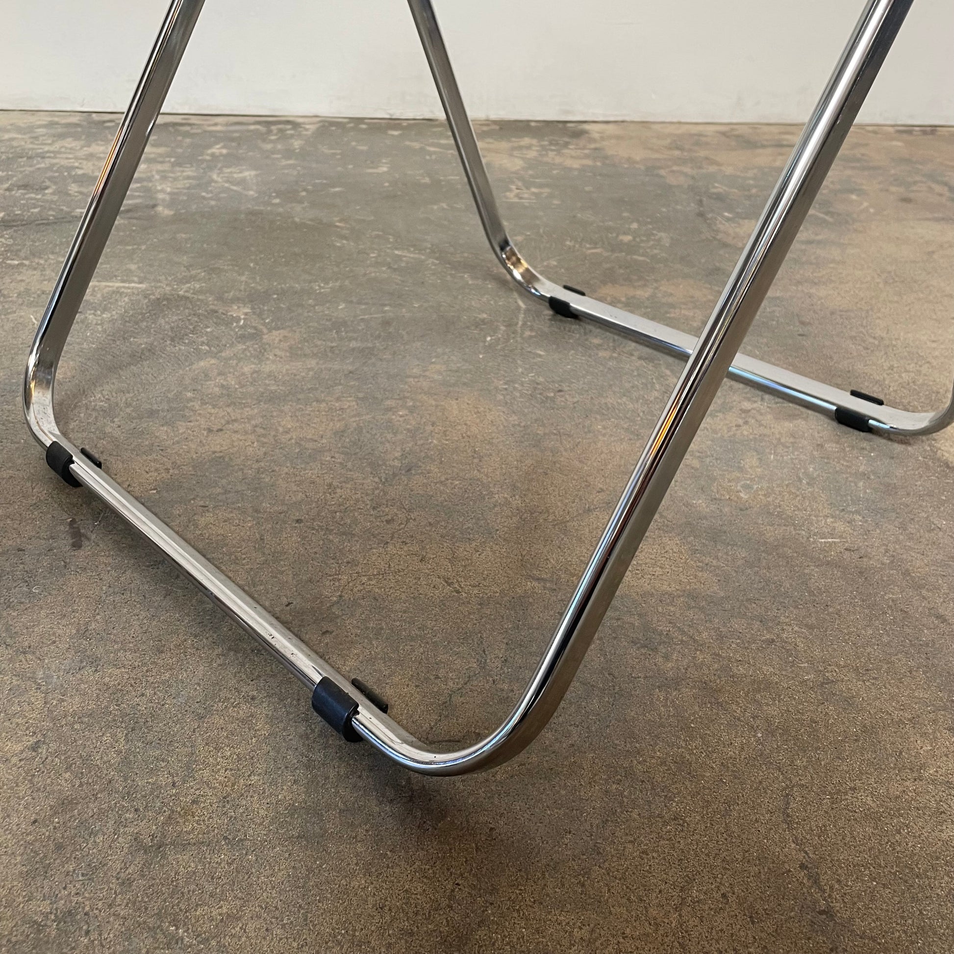 The Anonima Castelli Plia Folding Chair by Castelli, highlighted against a plain white background, echoes the iconic design of Giancarlo Piretti's Plia Folding Chairs and features the innovative "3-disc pin" mechanism.