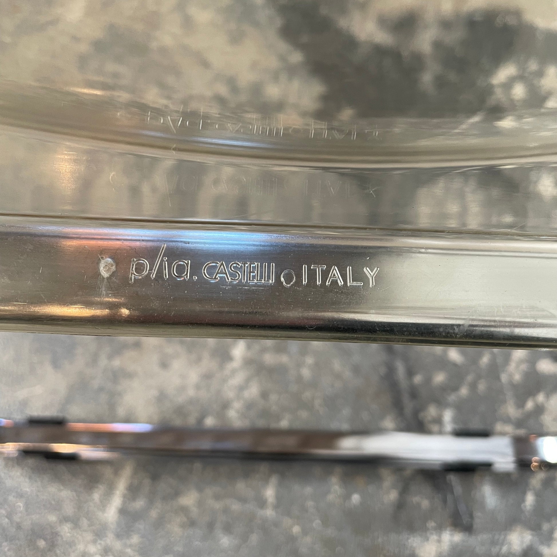 The Anonima Castelli Plia Folding Chair by Castelli, highlighted against a plain white background, echoes the iconic design of Giancarlo Piretti's Plia Folding Chairs and features the innovative "3-disc pin" mechanism.