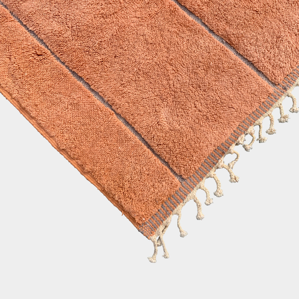 A **Moroccan** rug with tassels and fringes on a white background.