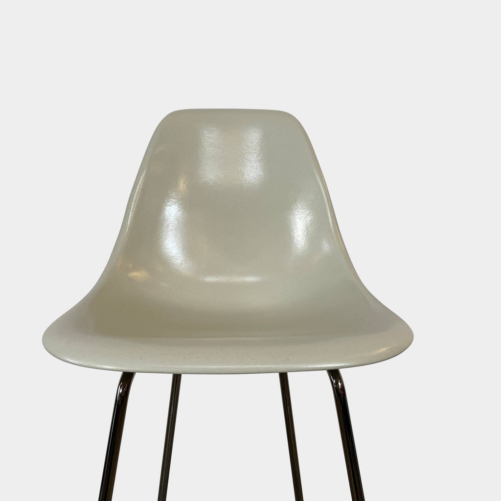 Two Herman Miller Eames Bar Height Stools with beige seats and black metal legs on a white background.