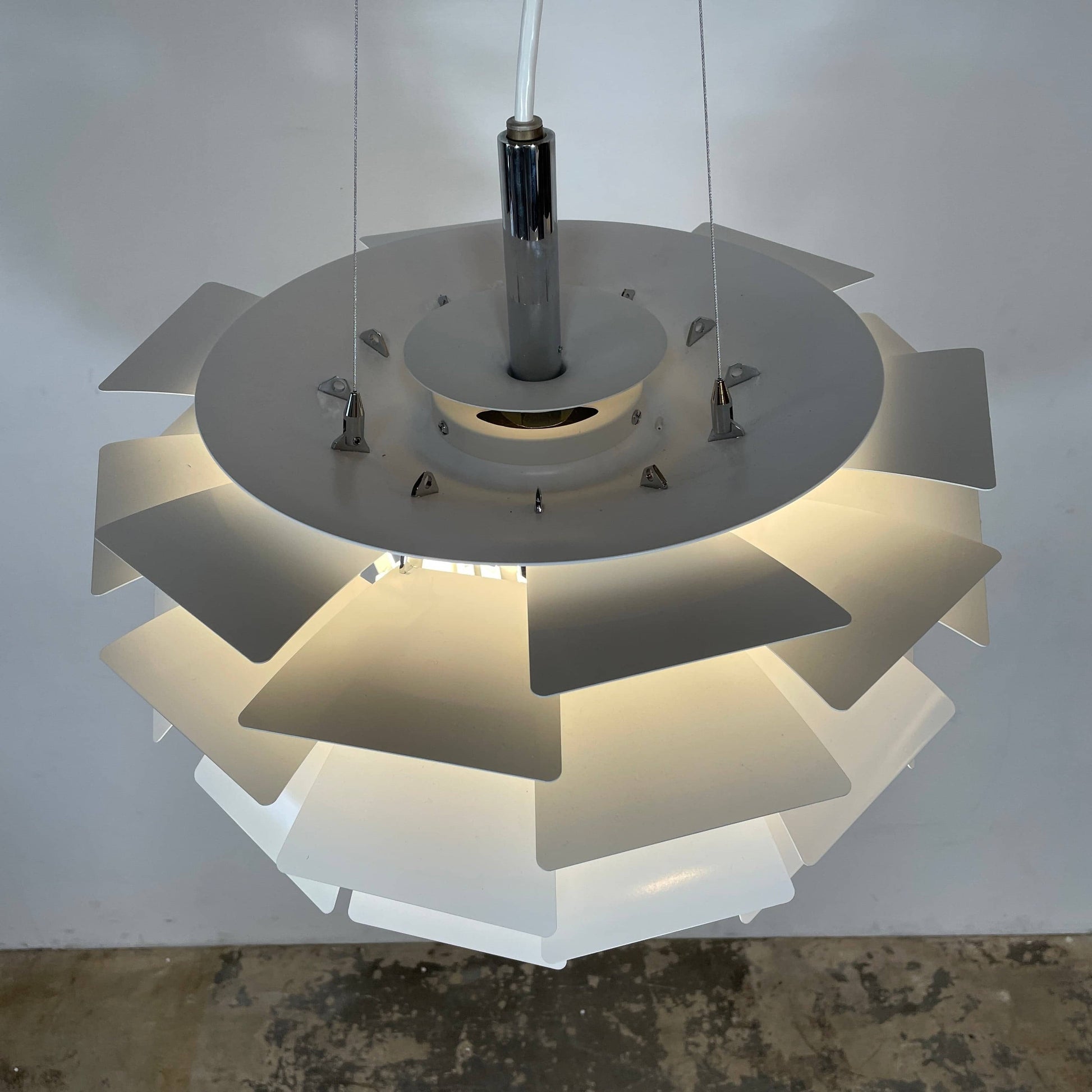 A Louis Poulsen PH Artichoke Suspension light with a white shade, providing glare-free light.