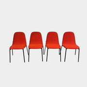 Four Zanotta Ella Dining Chairs, with their red fabric and black metal legs, are set in a row against a plain white background, showcasing the sleek design of this Italian brand.