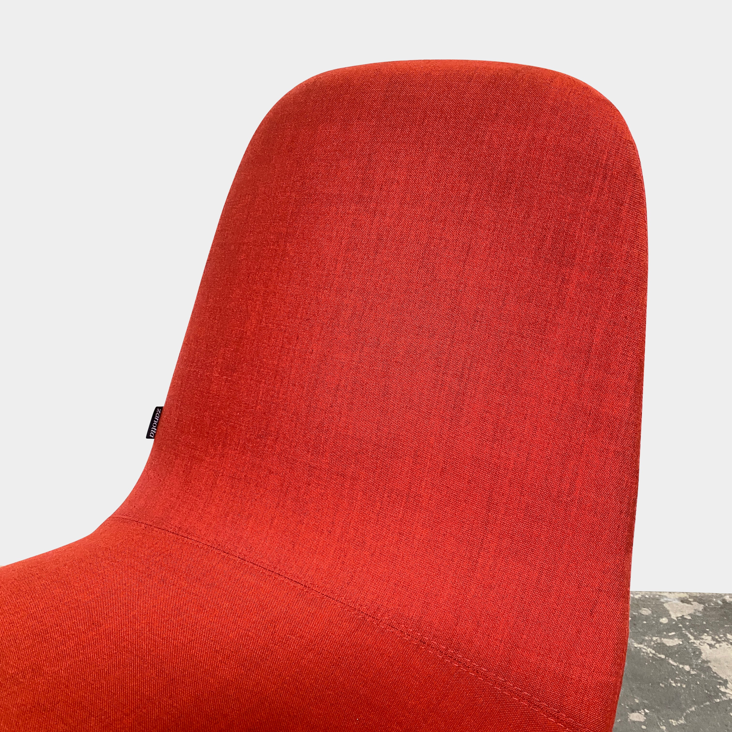 Four Zanotta Ella Dining Chairs, with their red fabric and black metal legs, are set in a row against a plain white background, showcasing the sleek design of this Italian brand.