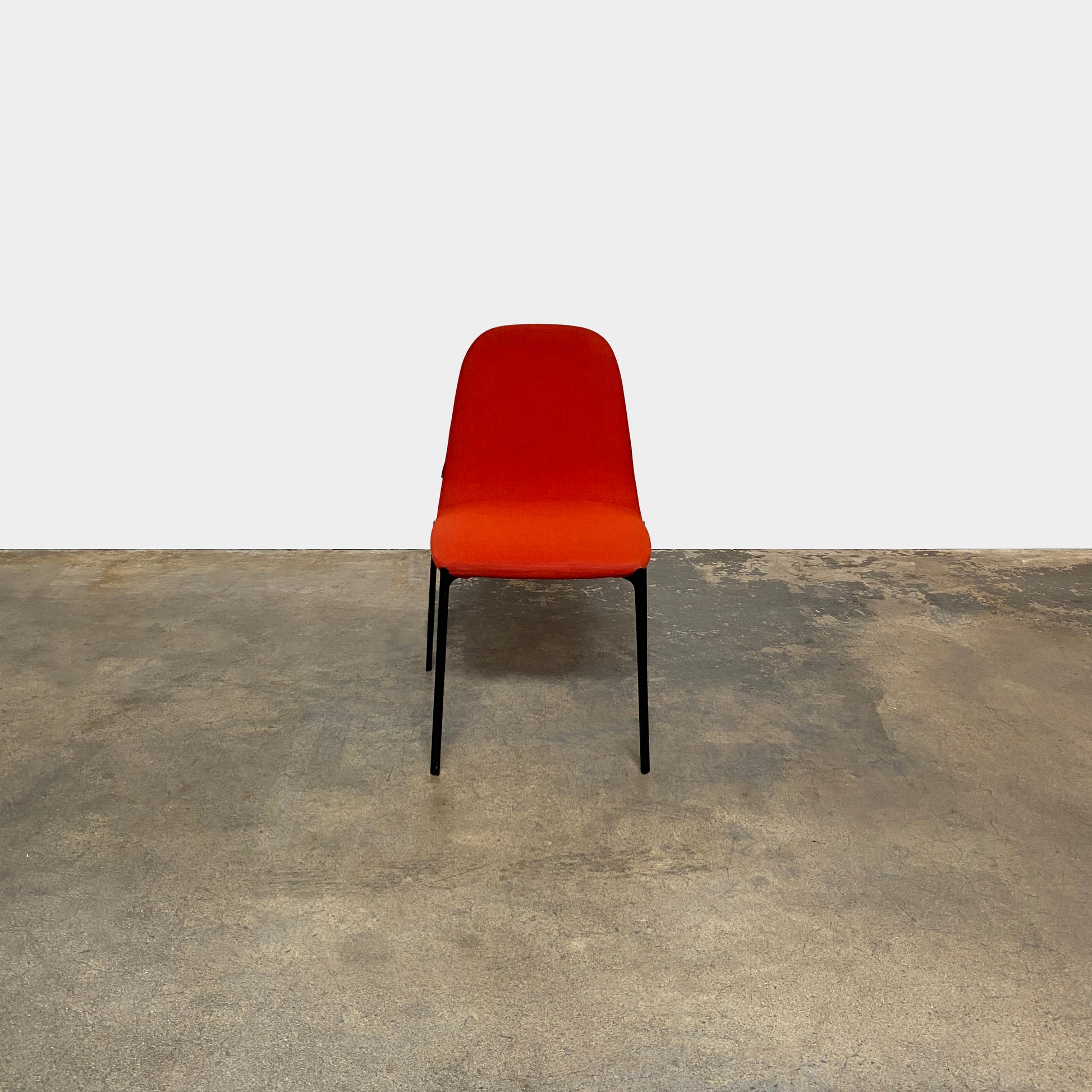 Four Zanotta Ella Dining Chairs, with their red fabric and black metal legs, are set in a row against a plain white background, showcasing the sleek design of this Italian brand.