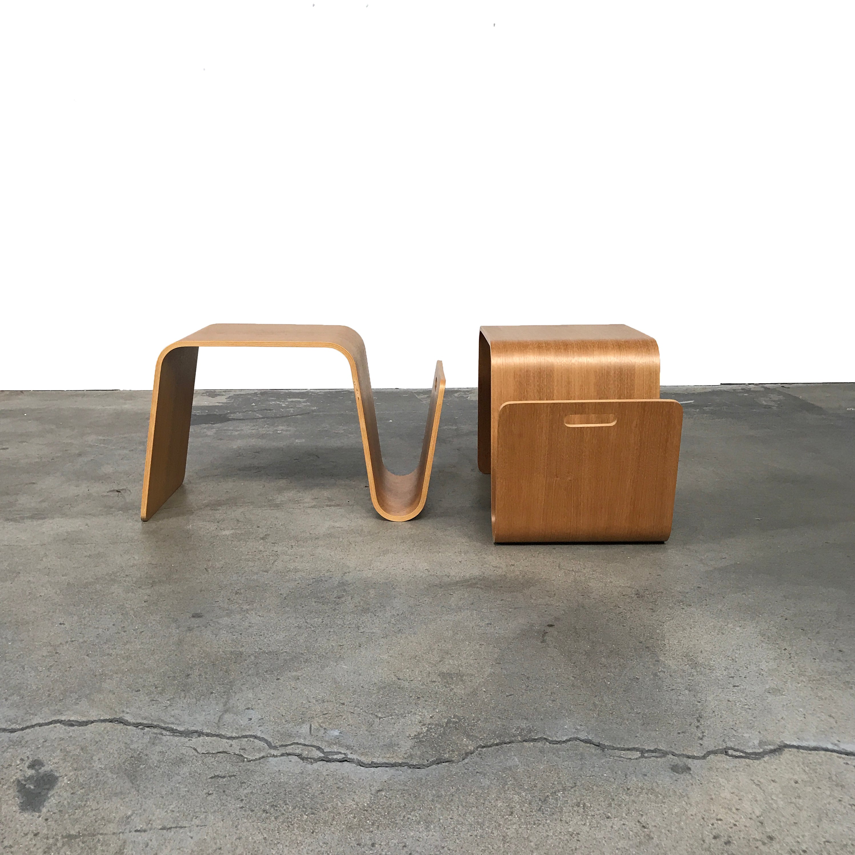 The Offi Mag Table by Offi is a minimalist wooden side table with an angular, wave-inspired design. It serves as a multifunctional table or compact workstation, featuring a curved slot for storage—displayed on a plain white background.