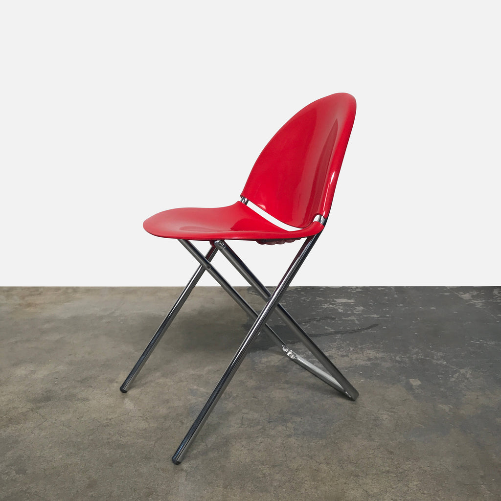 A Fol D Folding Chair - Red by XO against a white wall.
