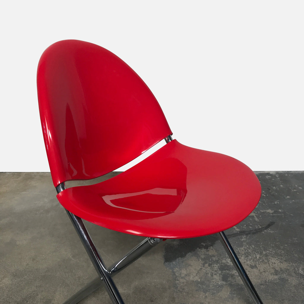 A Fol D Folding Chair - Red by XO against a white wall.